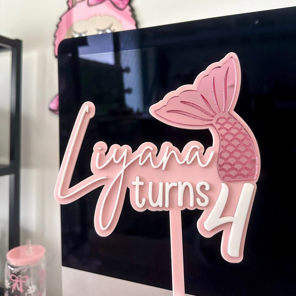 Custom mermaid tail cake topper made from layered acrylic, featuring a personalised name and age in a bold, cursive font.