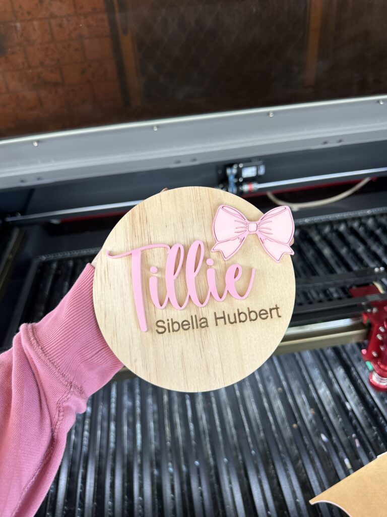 A custom, handcrafted, baby announcement plaque in a bow theme, made from layered acrylic, with a personal touch.