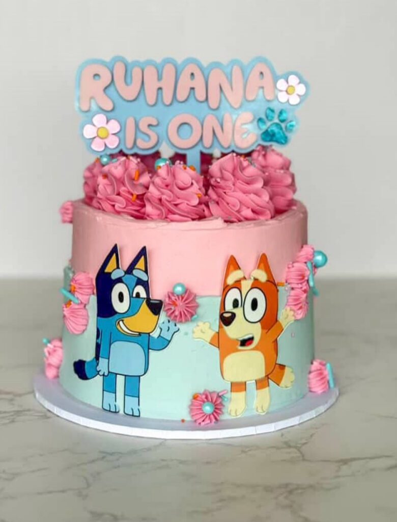 layered acrylic cake topper with mirrored finish, featuring Bluey and Daisy characters with paw prints and a personalised.