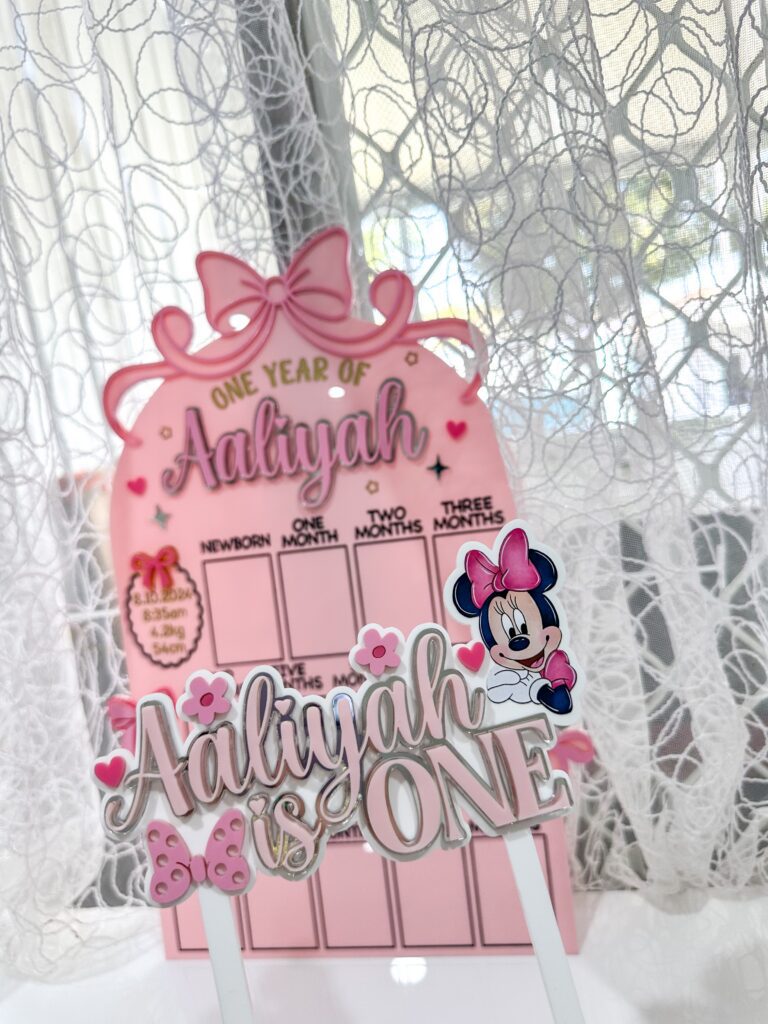 acrylic photo board with a bow theme, personalised with a baby's name and first year photos.