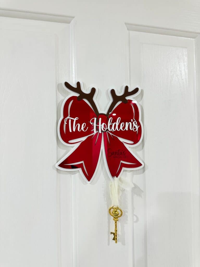 Personalised Christmas bow door hanger made from layered acrylic with a mirrored finish, ready for personalisation.