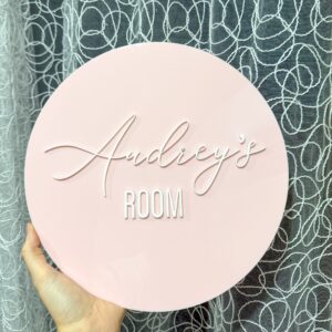 A custom, handcrafted, acrylic door sign for kids' rooms and nurseries, featuring a child's name in a bold, cursive font.