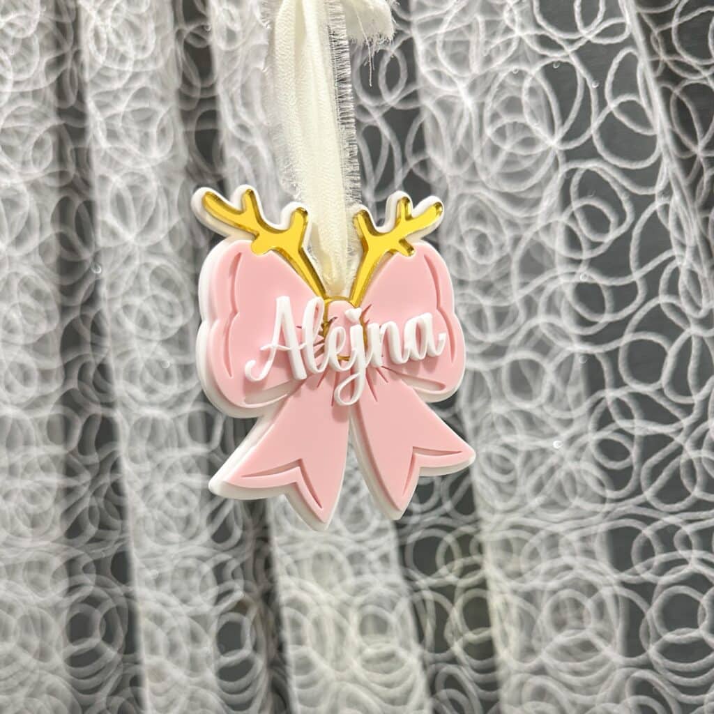 A custom, handcrafted, layered acrylic bow Christmas ornament, personalised with a name, ready for personalisation.