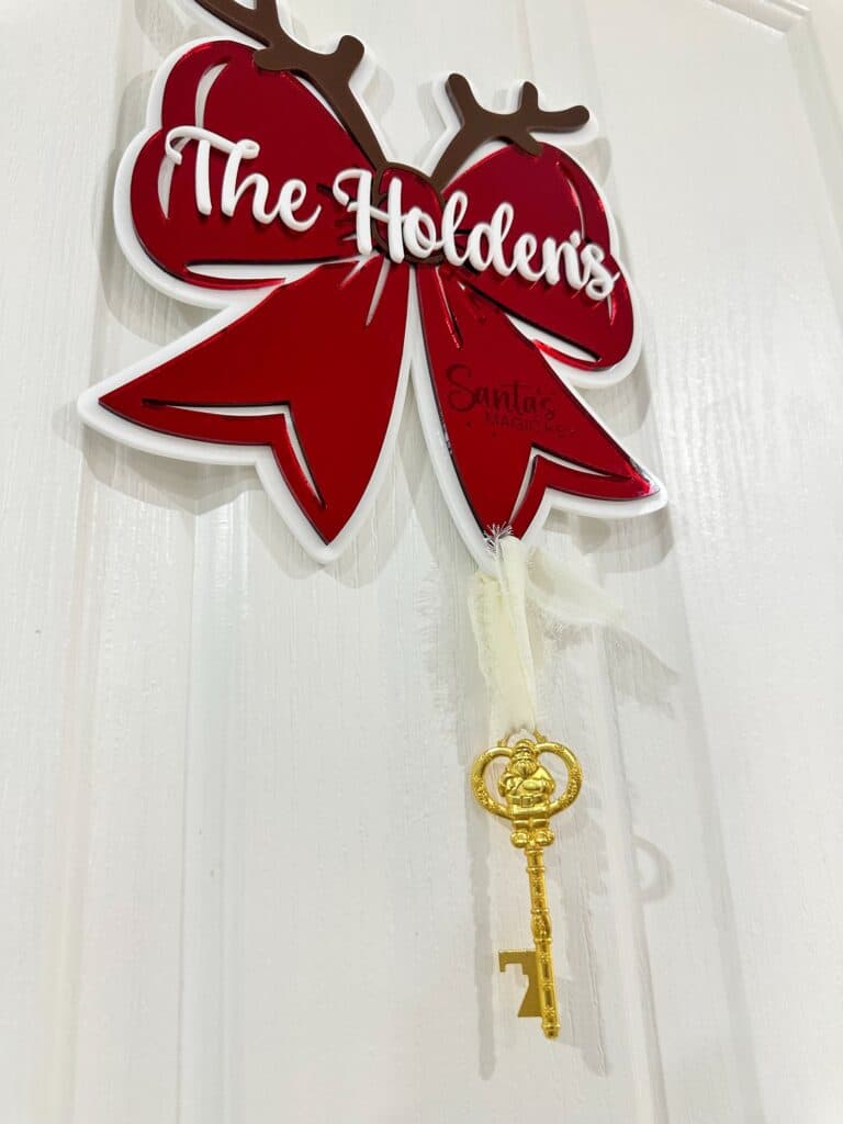 Personalised Christmas Bow Door Hanger – Santa’s Key, made from layered acrylic with a mirrored finish.