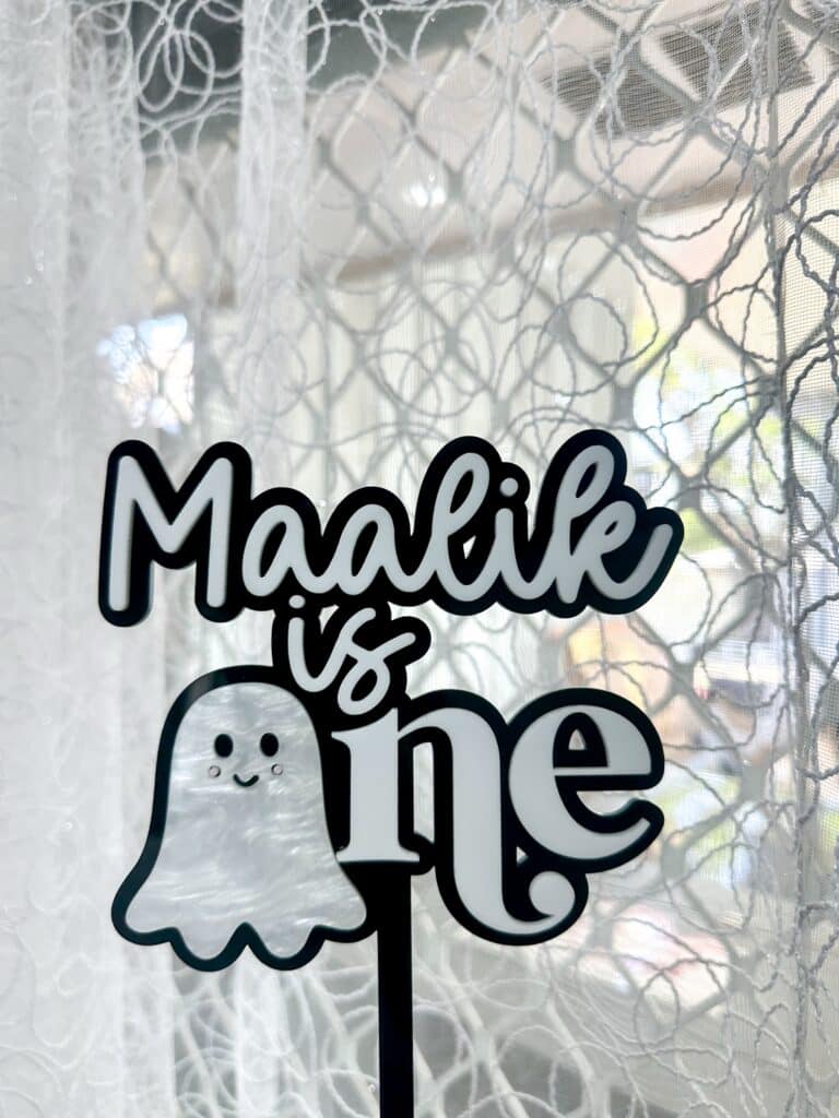 Halloween cake topper made of layered acrylic, featuring a ghost design and personalised with a name and age in a custom.