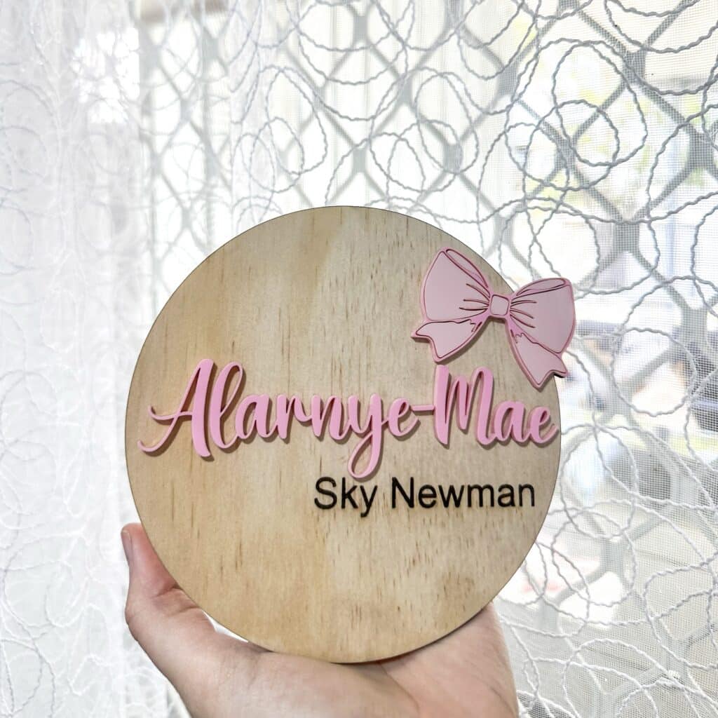 Personalised baby announcement plaque featuring engraved wood with pink acrylic bow detailing, announcing your little girl's.