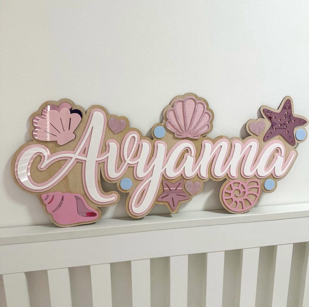 Personalised mermaid name sign 'Ayyanna' with shells, starfish, hearts and bubble accents on a wooden base.