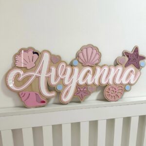 Personalised mermaid name sign 'Ayyanna' with shells, starfish, hearts and bubble accents on a wooden base.
