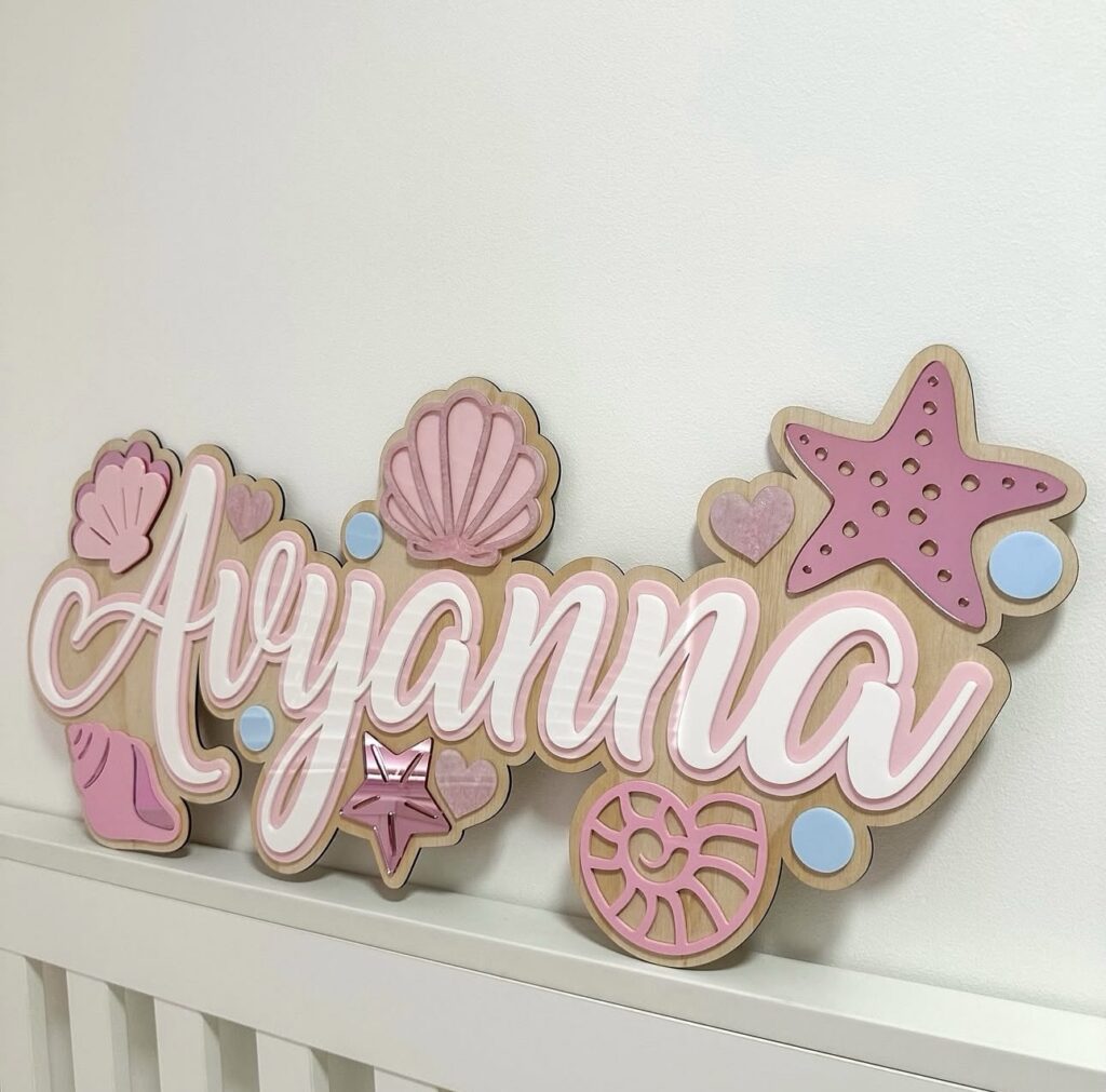 Personalised layered acrylic mermaid name plaque 'Aryanna' with starfish, seashells and blue bubble accents.