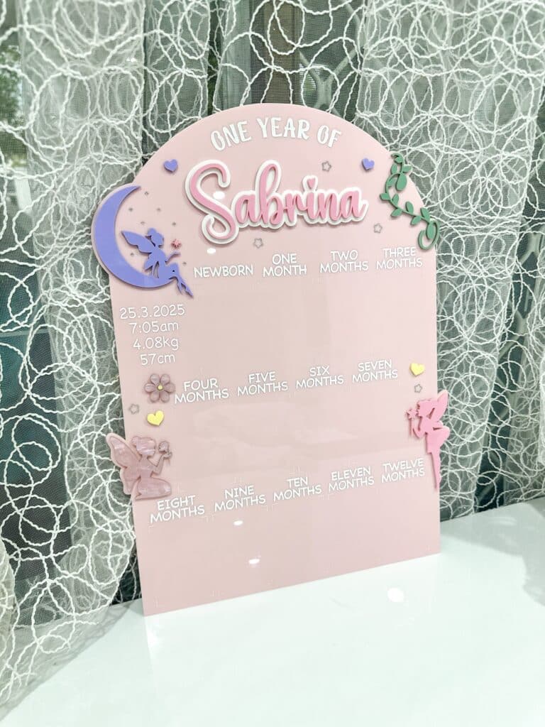 Clear personalised acrylic name plaque photographed on a neutral background.