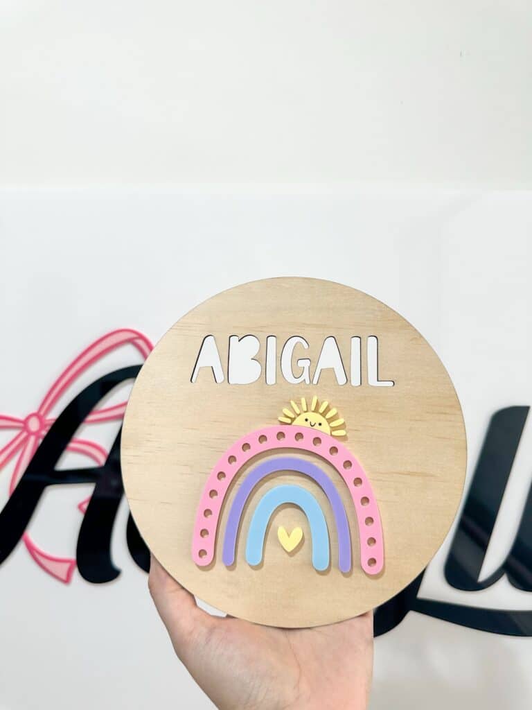 Personalised rainbow name plaque with hearts and sunshine, made from layered acrylic. Custom, handcrafted, and bespoke.